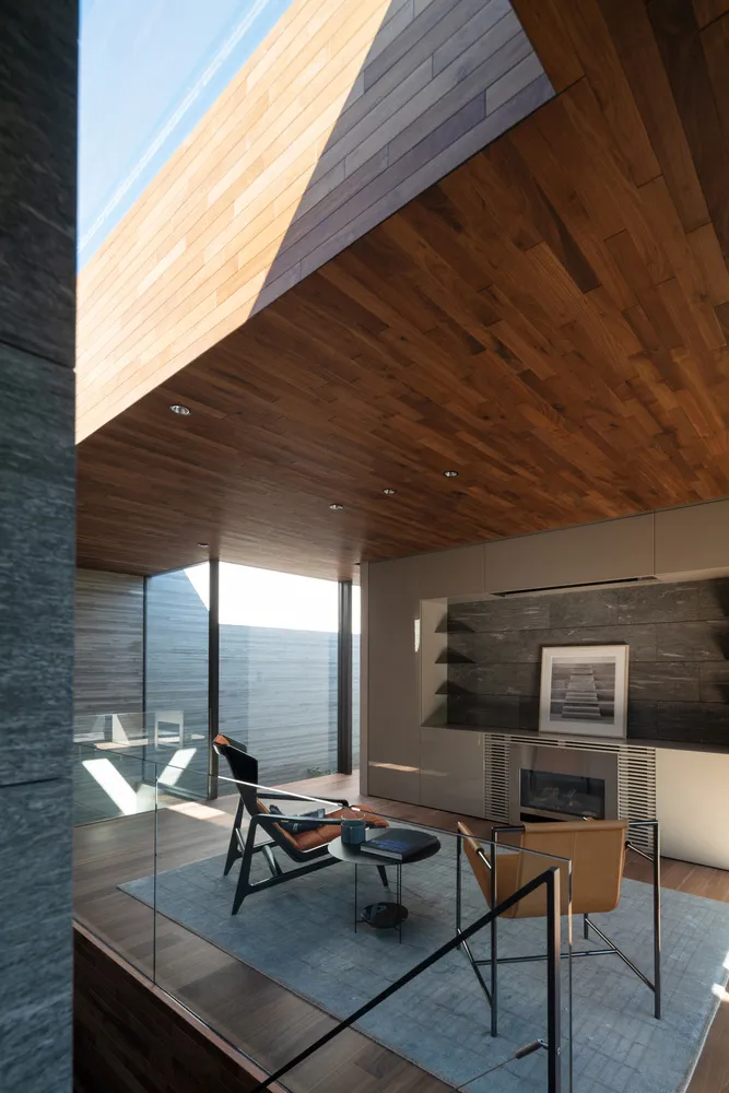 A modern living room with a wooden ceiling and floor, featuring contemporary furniture and a fireplace.