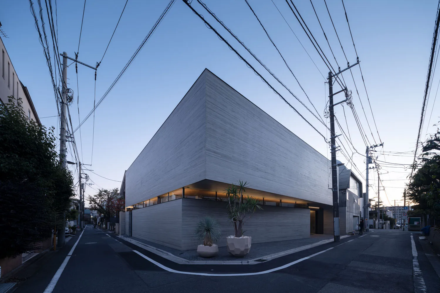 Modern house with a minimalist design, featuring concrete exterior and a prominent roofline.