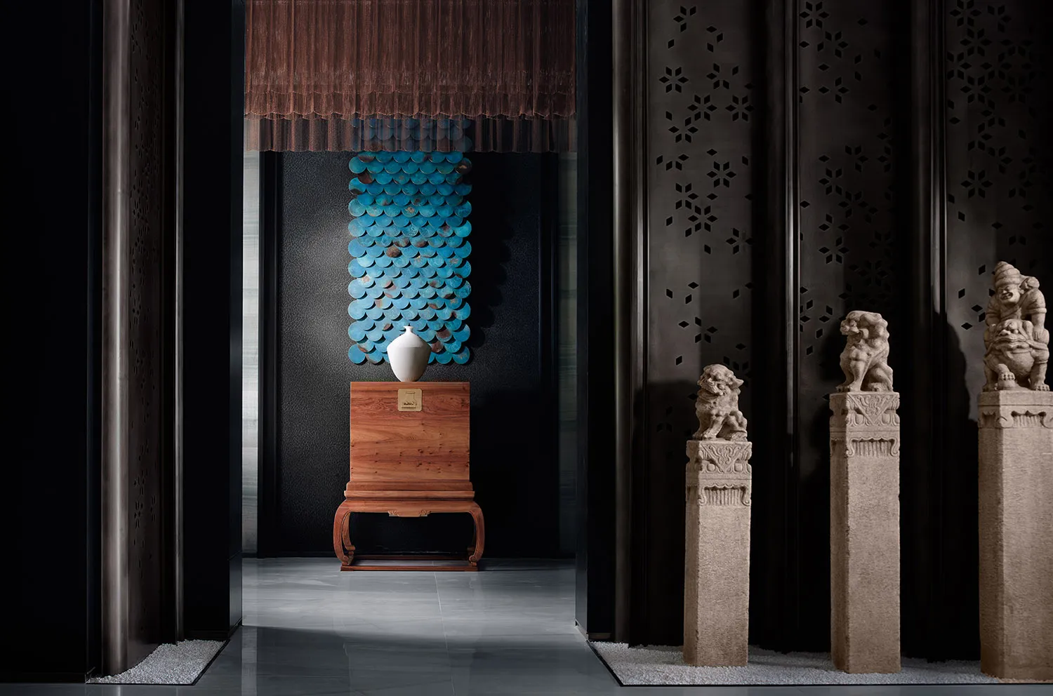 A modern interior design display featuring a wooden pedestal with a white vase, blue wall tiles, and lion statues.