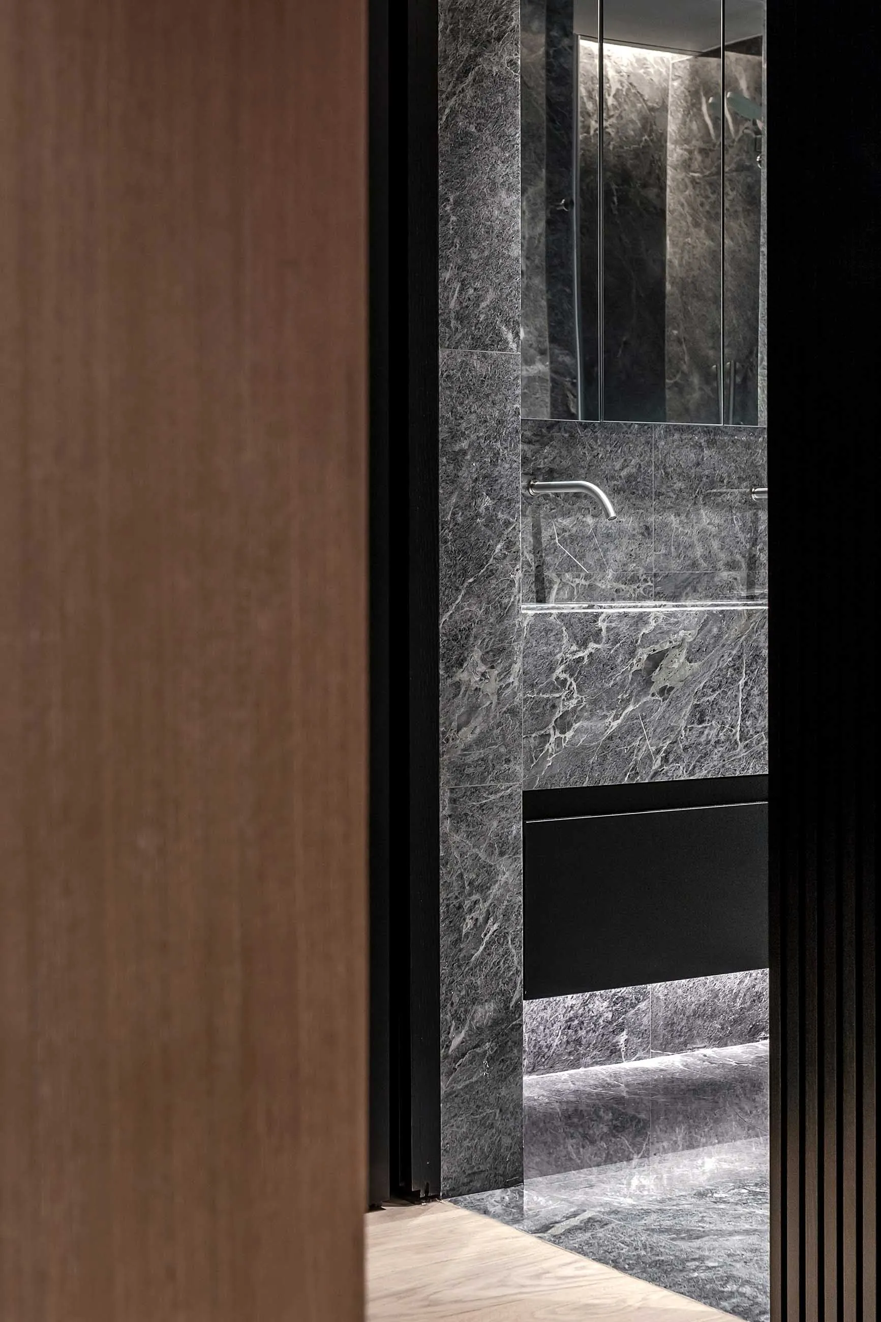 Modern minimalist bathroom with marble walls and black accents.