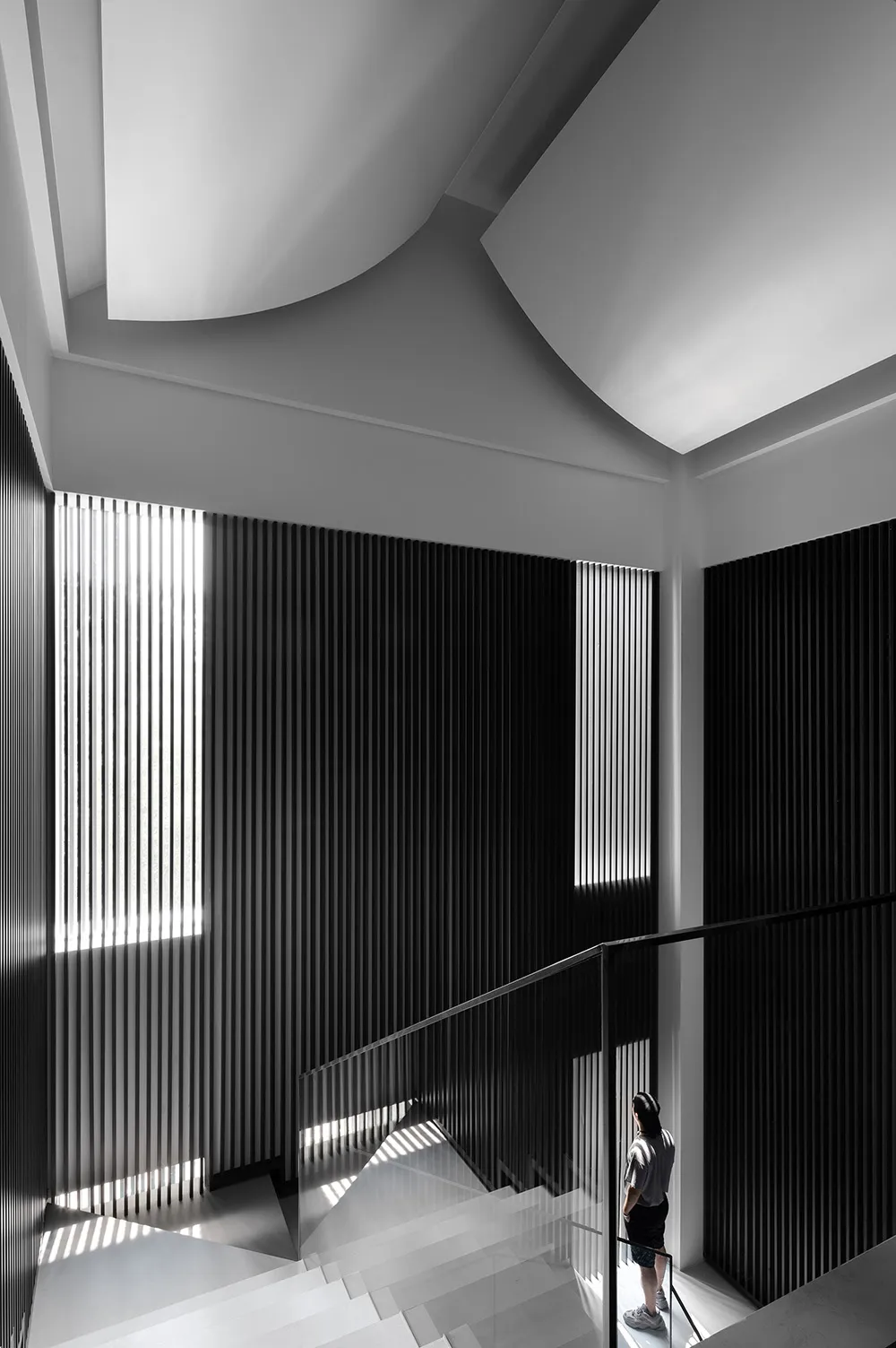 A minimalist staircase with glass railings and a geometric design.