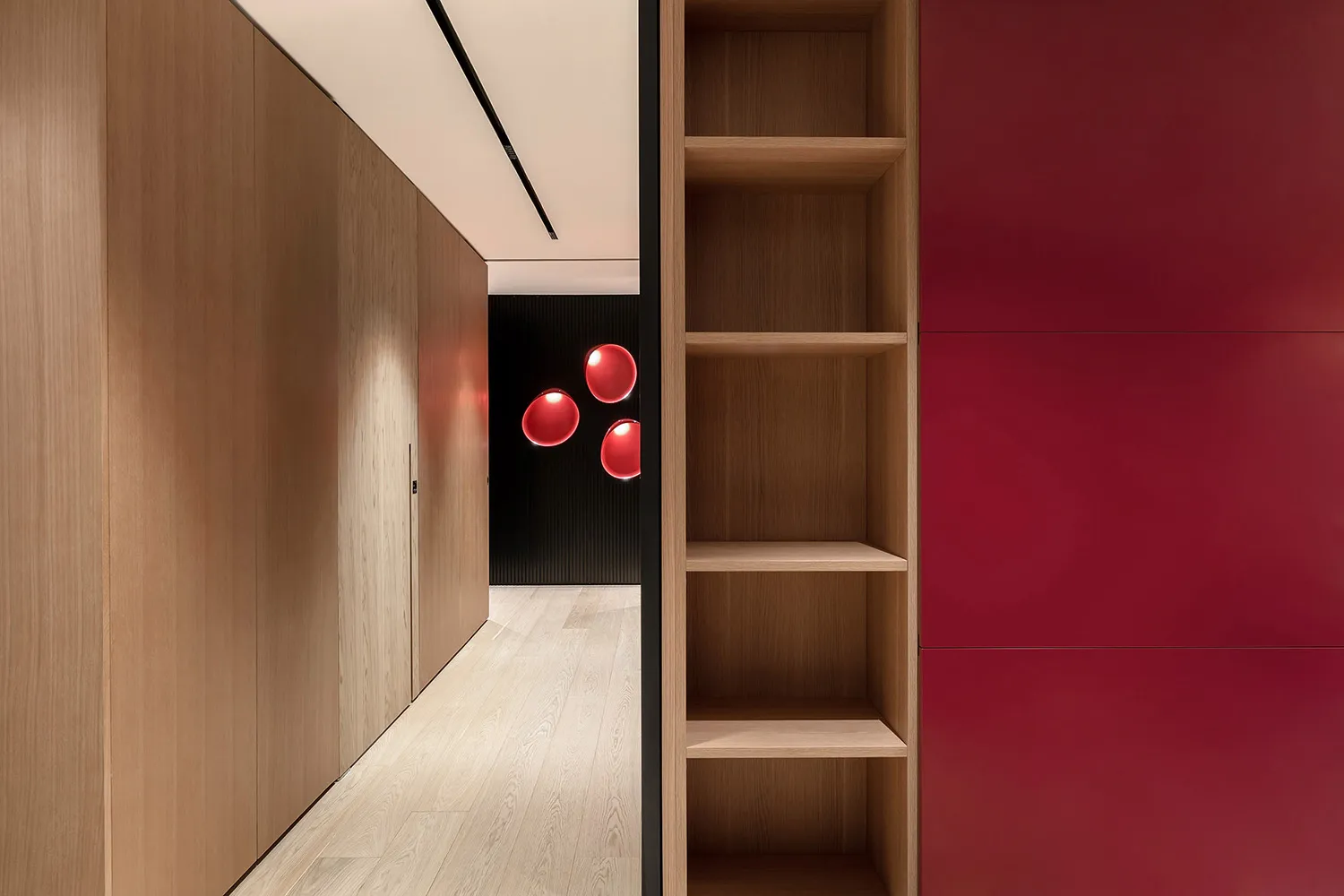 Modern minimalist walk-in closet with wooden shelves and red accents.