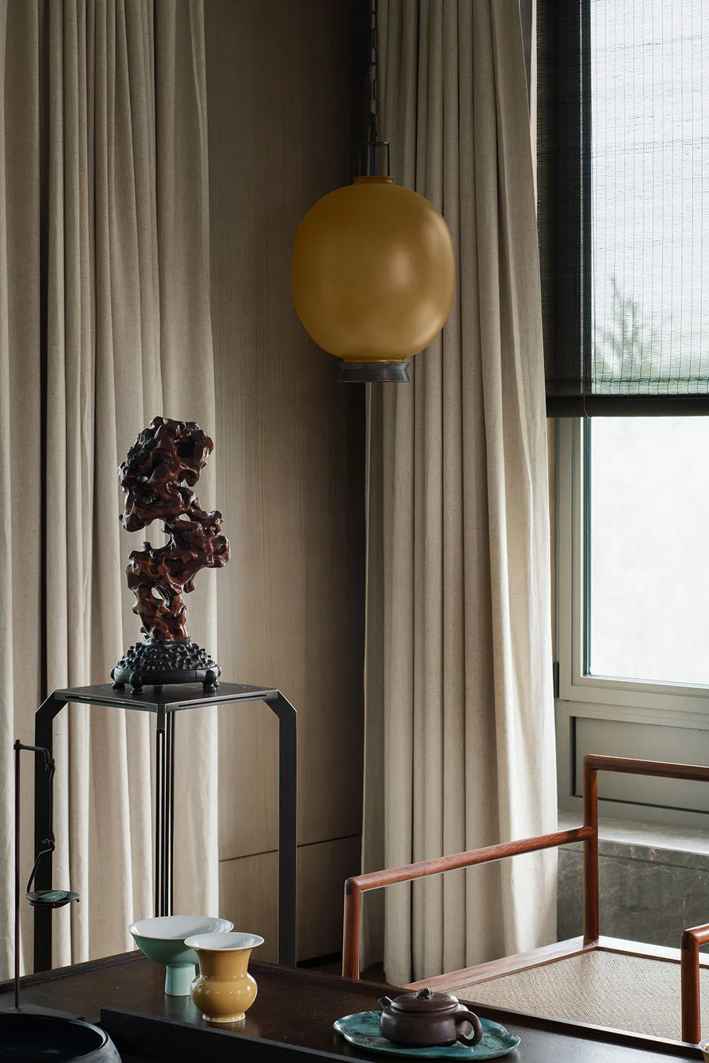 Modern minimalist living room with wood furniture, fabric curtains, and ceramic vases and teapot.