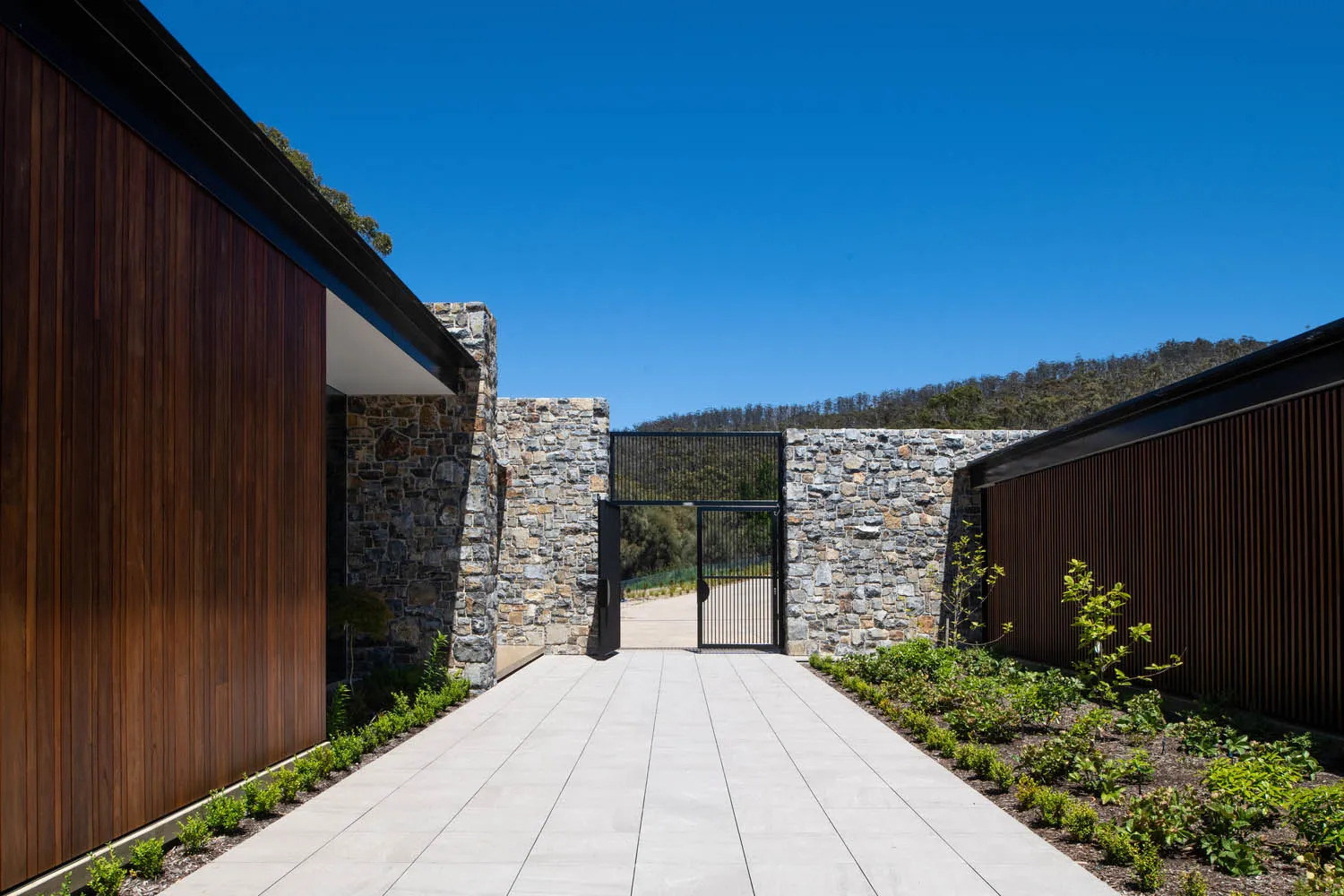 Modern house exterior featuring stone, concrete, and timber materials.