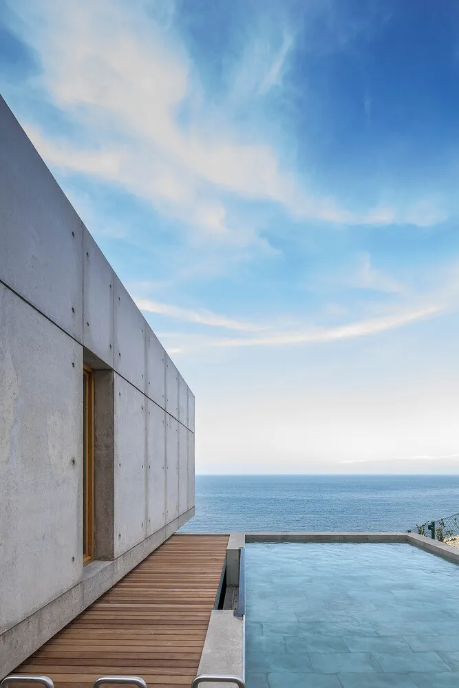 Modern concrete building by the ocean with a swimming pool.