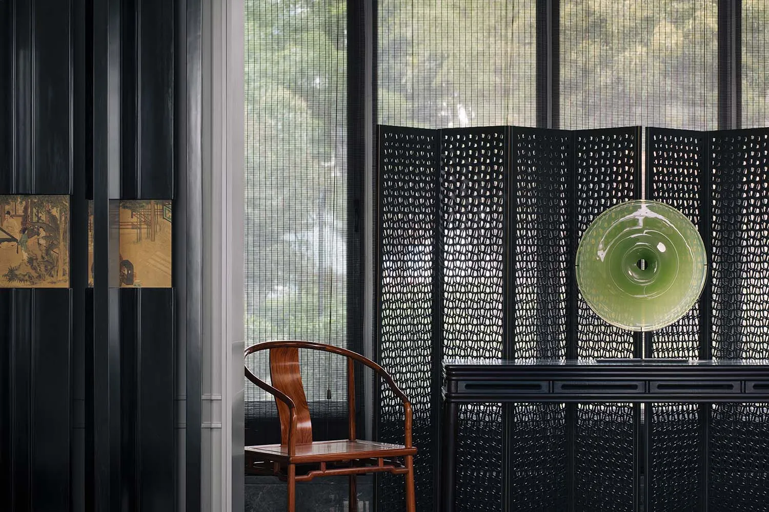 A minimalist office space featuring a black metal screen, modern furniture, and a green glass art piece.