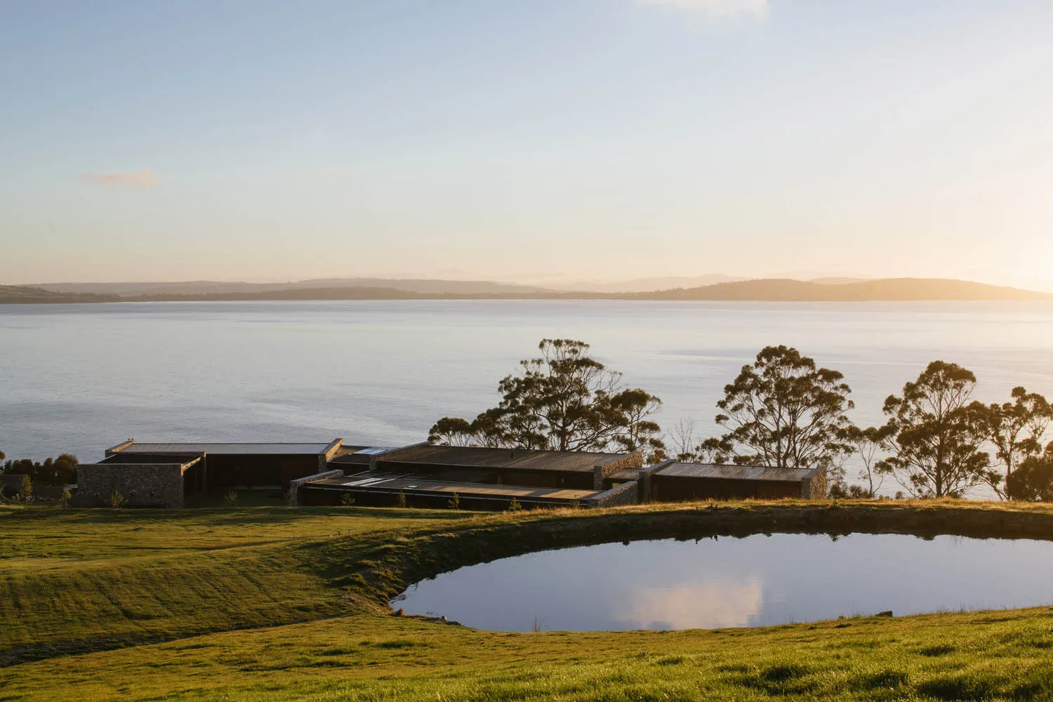 A modern home with a stone facade and expansive waterfront view.