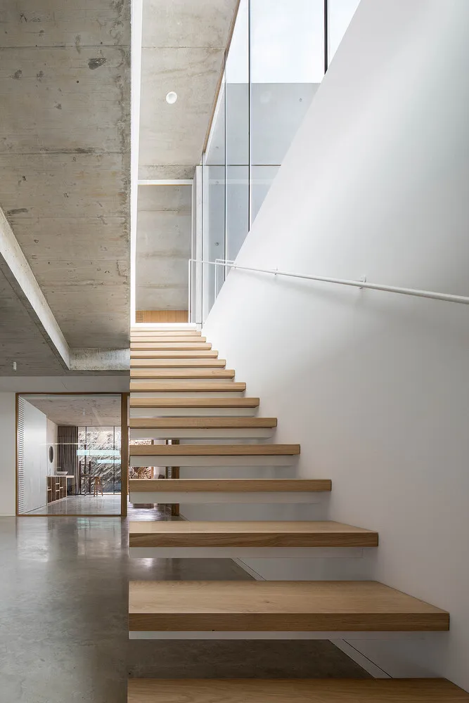 A modern staircase with wooden steps and concrete walls.