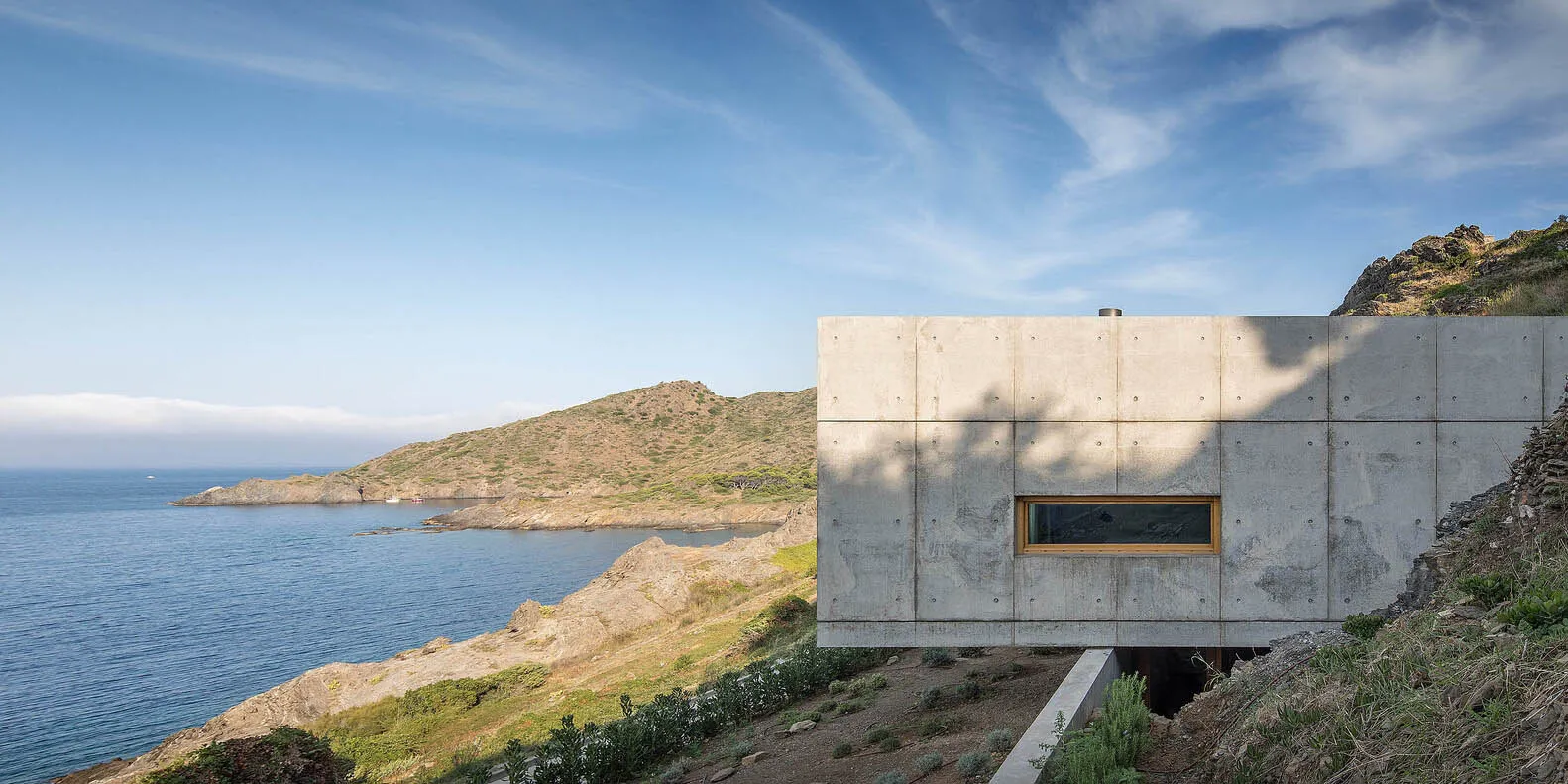 A minimalist vacation home featuring a concrete exterior with a small window.