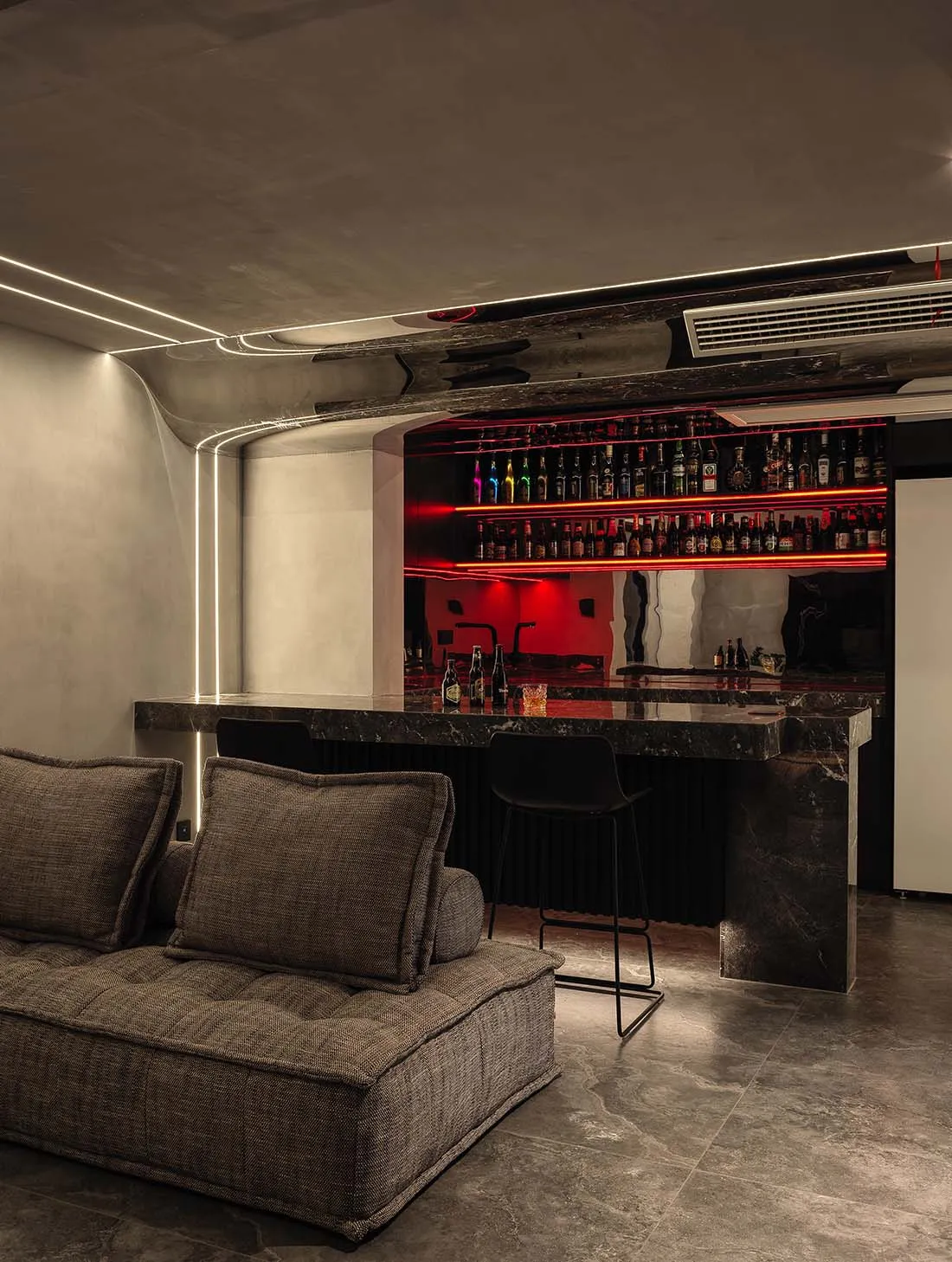 A modern industrial-style bar with black marble countertops and a black seating area.