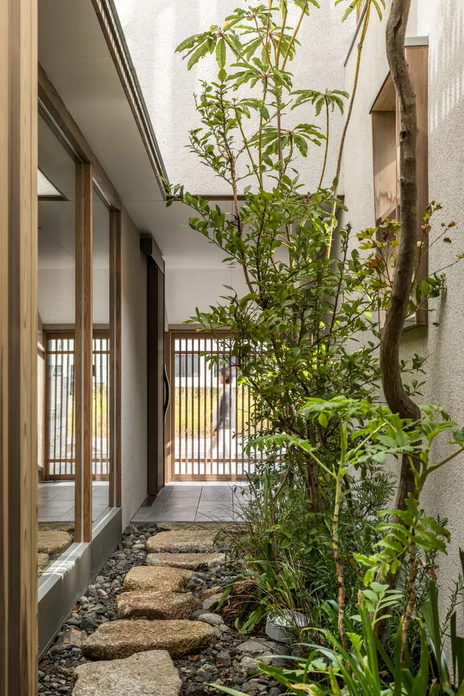 A modern residential entryway featuring natural stone pavers and green foliage.
