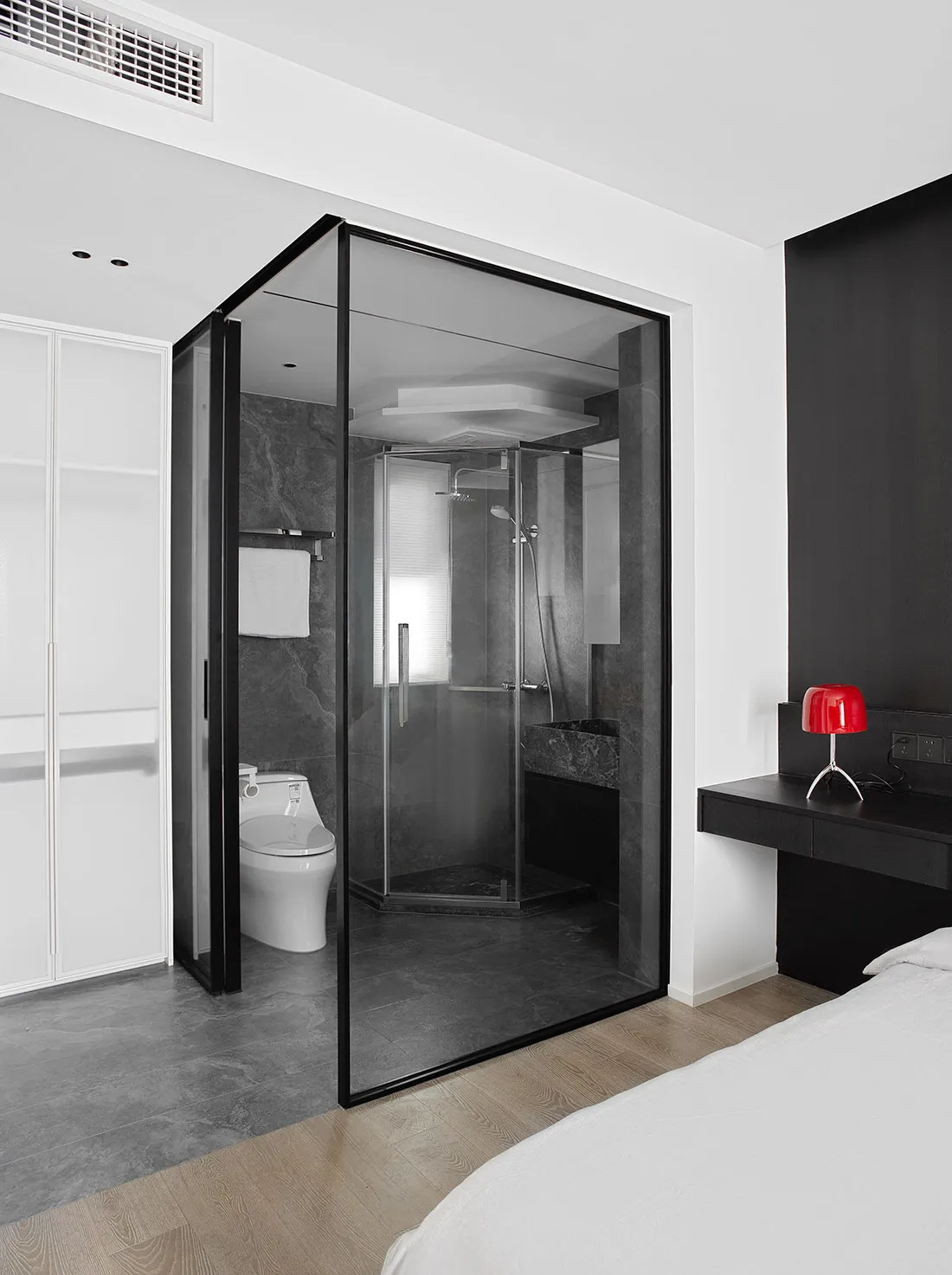 Modern minimalist bathroom suite featuring black glass shower enclosure, marble accents, and concrete floor.