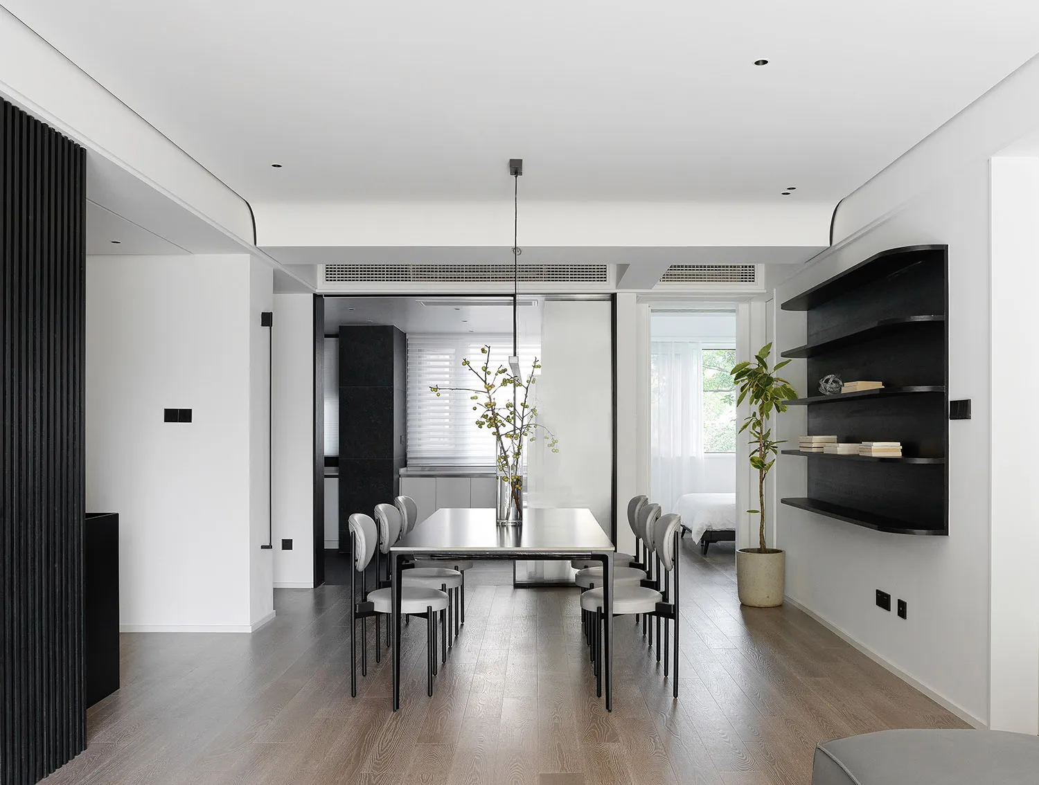 Modern minimalist living room with a wooden floor, white walls, and simple furniture arrangement.
