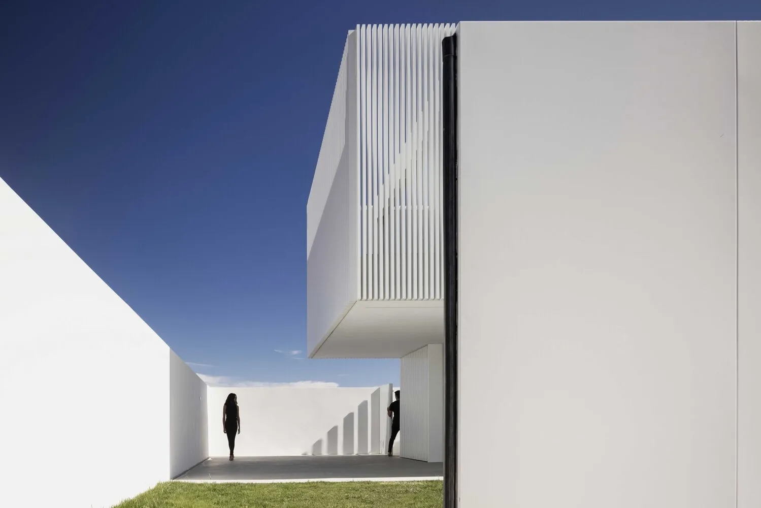 Two people in a minimalist white concrete architectural exterior
