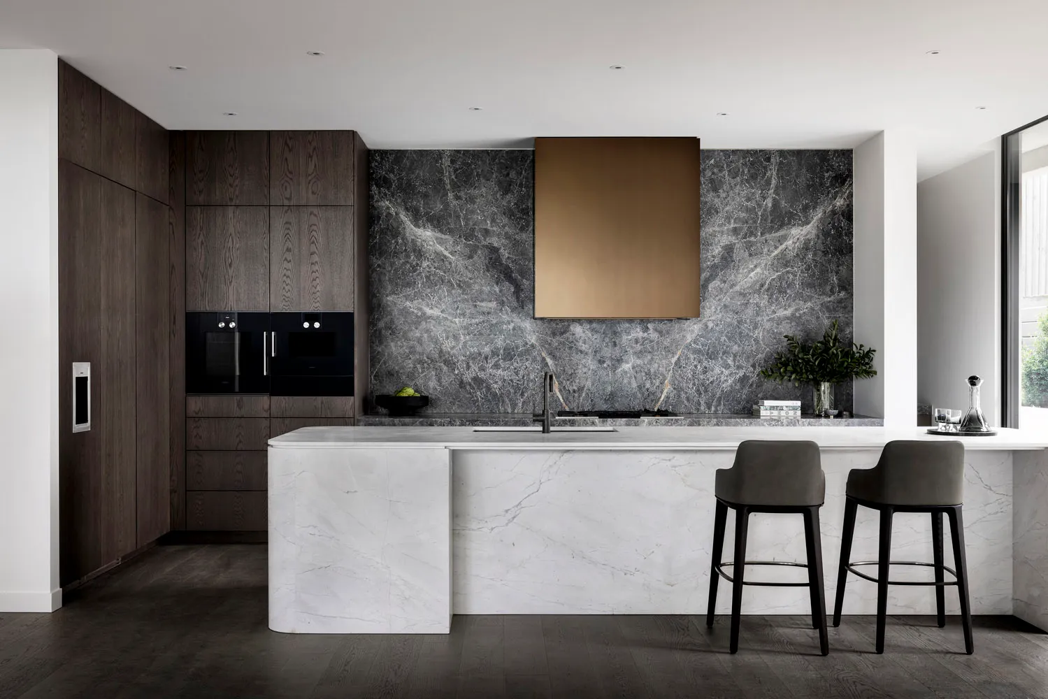Contemporary residential kitchen featuring dark wood cabinets, a marble backsplash, and a marble kitchen island.