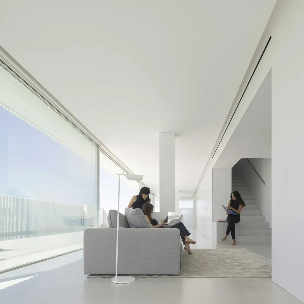 A modern minimalist living room with large glass windows.