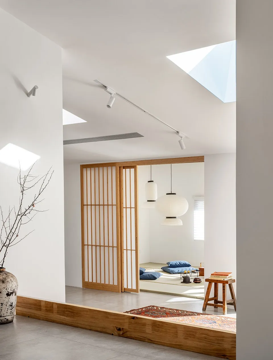 A minimalist living room with wooden elements, including a wooden floor, wooden furniture, and a wooden screen.