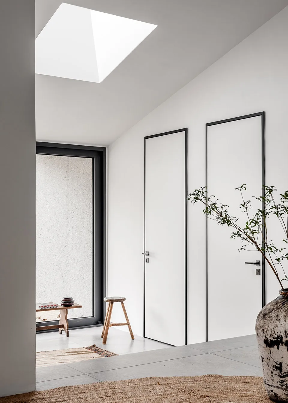 A minimalist white interior with concrete walls and a skylight