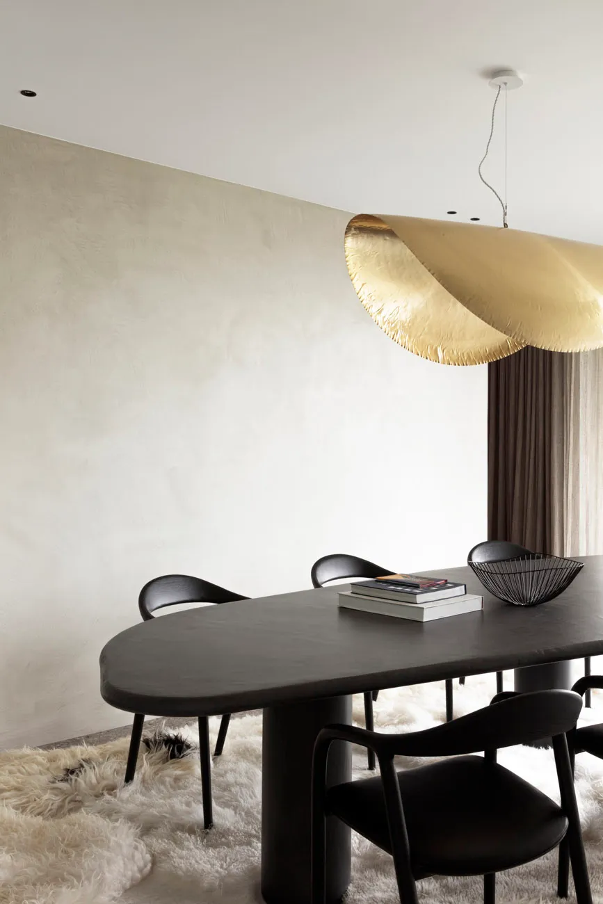 Modern dining room featuring a sleek metal table and chairs with a textured wall and plush rug.