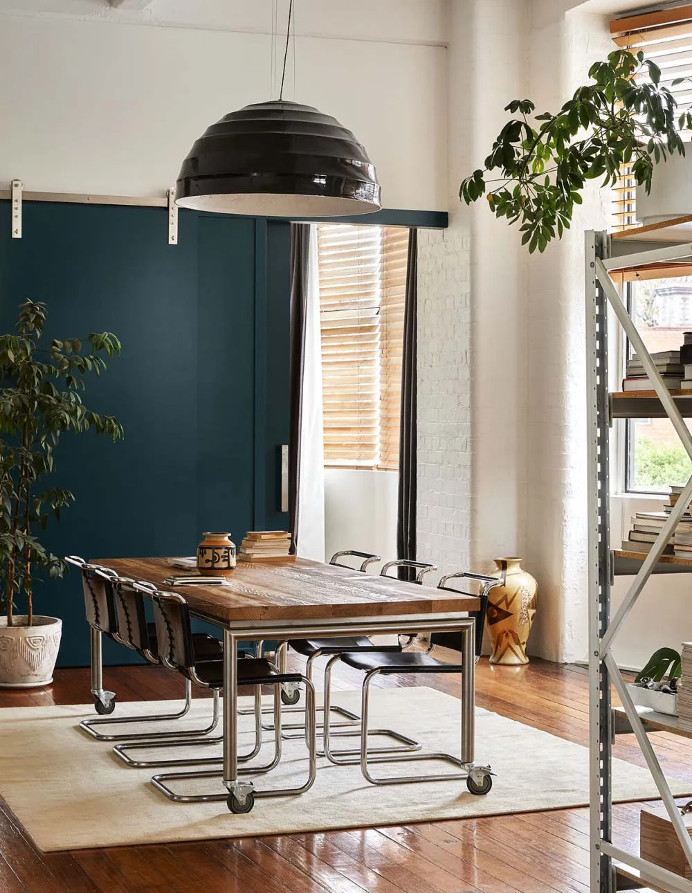 A modern, industrial-style dining room with a wooden table and metal chairs.