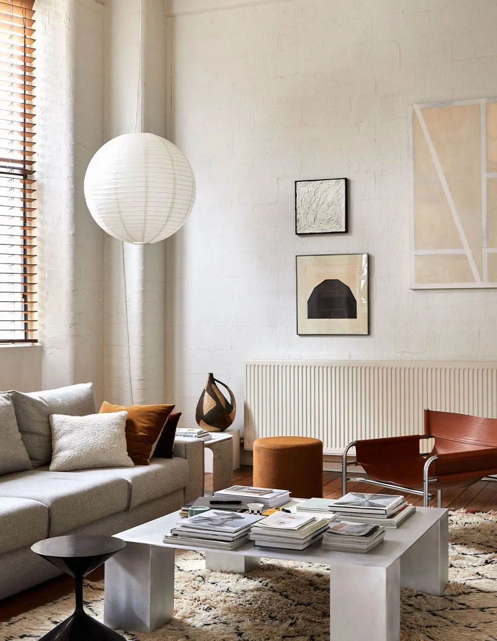 A modern minimalist living room with a white sofa, a coffee table, and various decorative elements including a hanging light