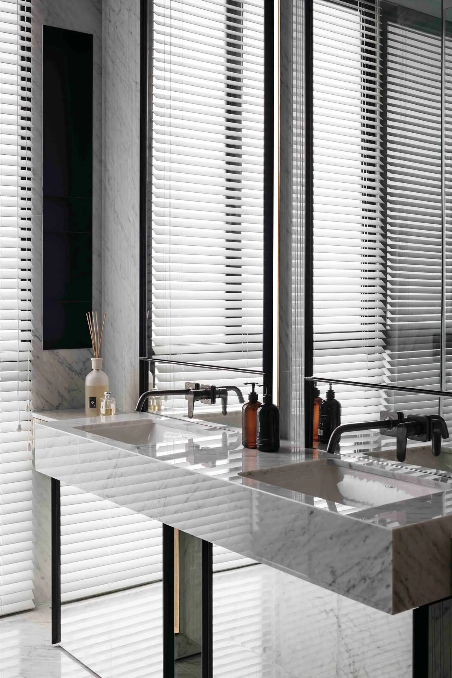 A modern, minimalist bathroom with white marble finishes and a sleek, floating sink.