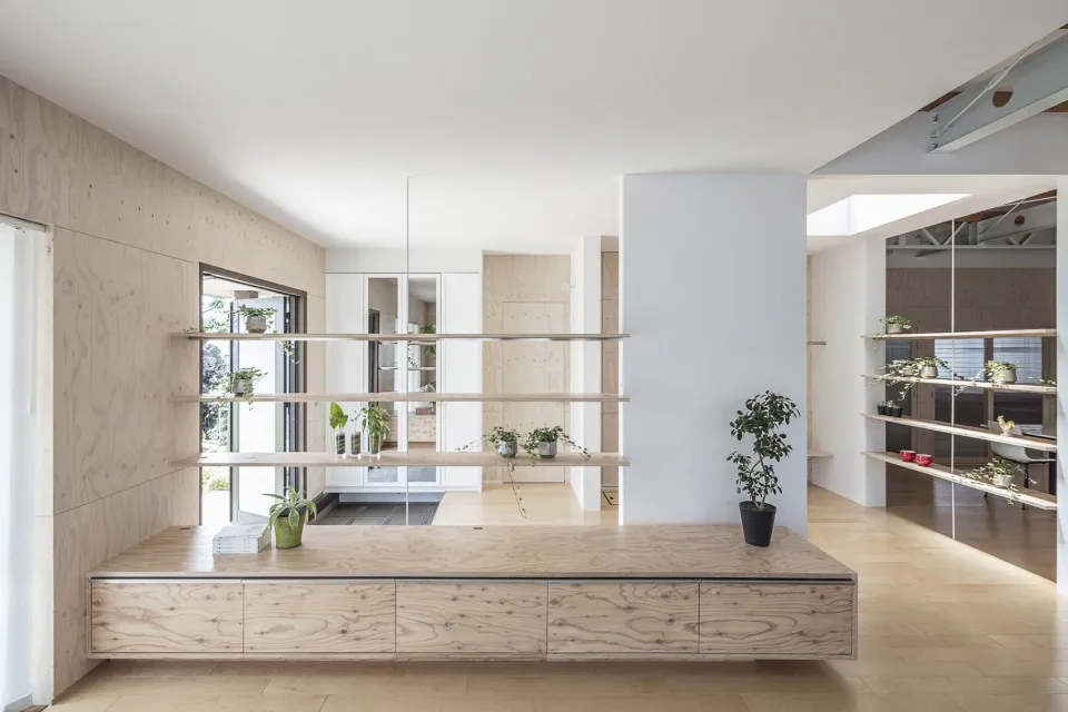 Modern minimalist living room with wooden shelving and plants.
