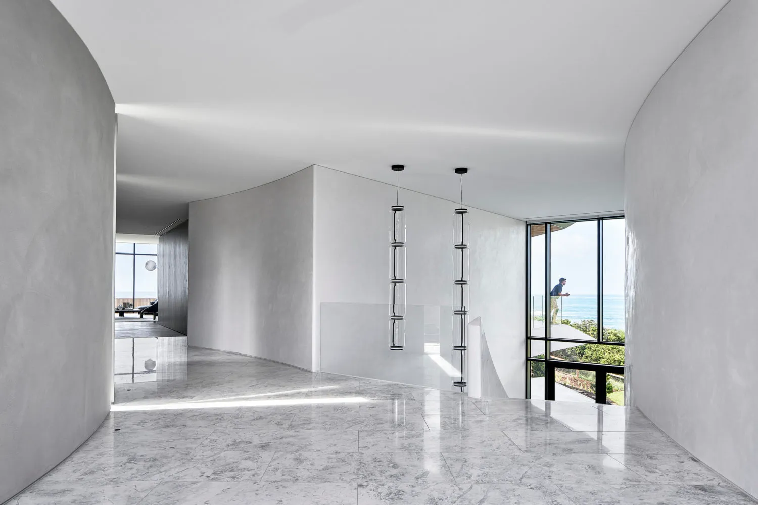 A minimalist residential interior with marble flooring, glass walls, and concrete accents.