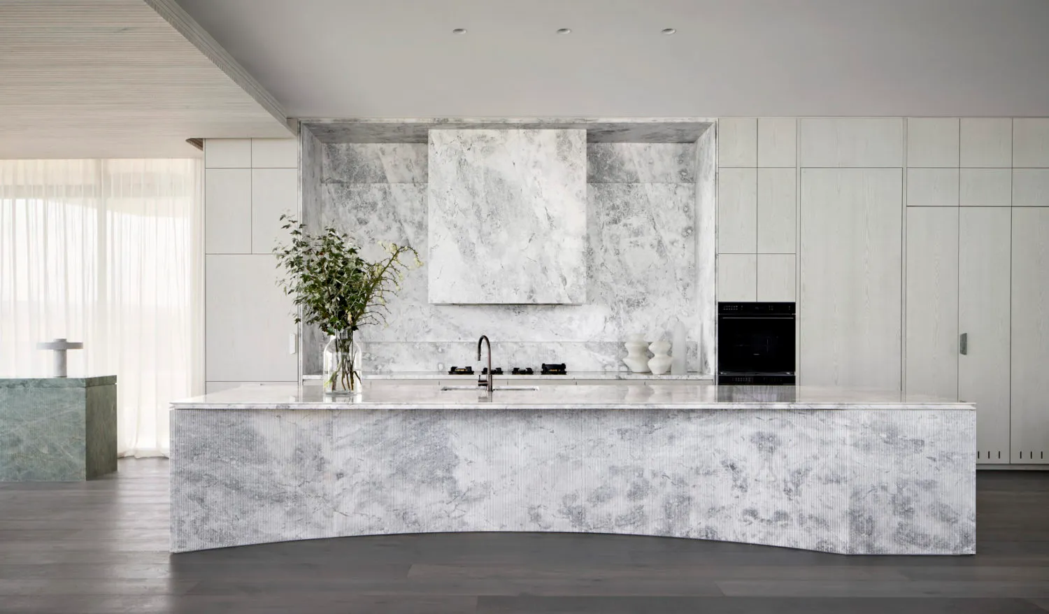 A modern kitchen featuring marble countertops and backsplash with minimalist design.