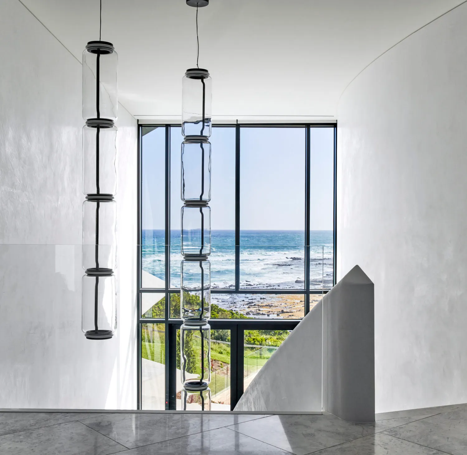 Modern residential interior with large glass window showcasing coastal view