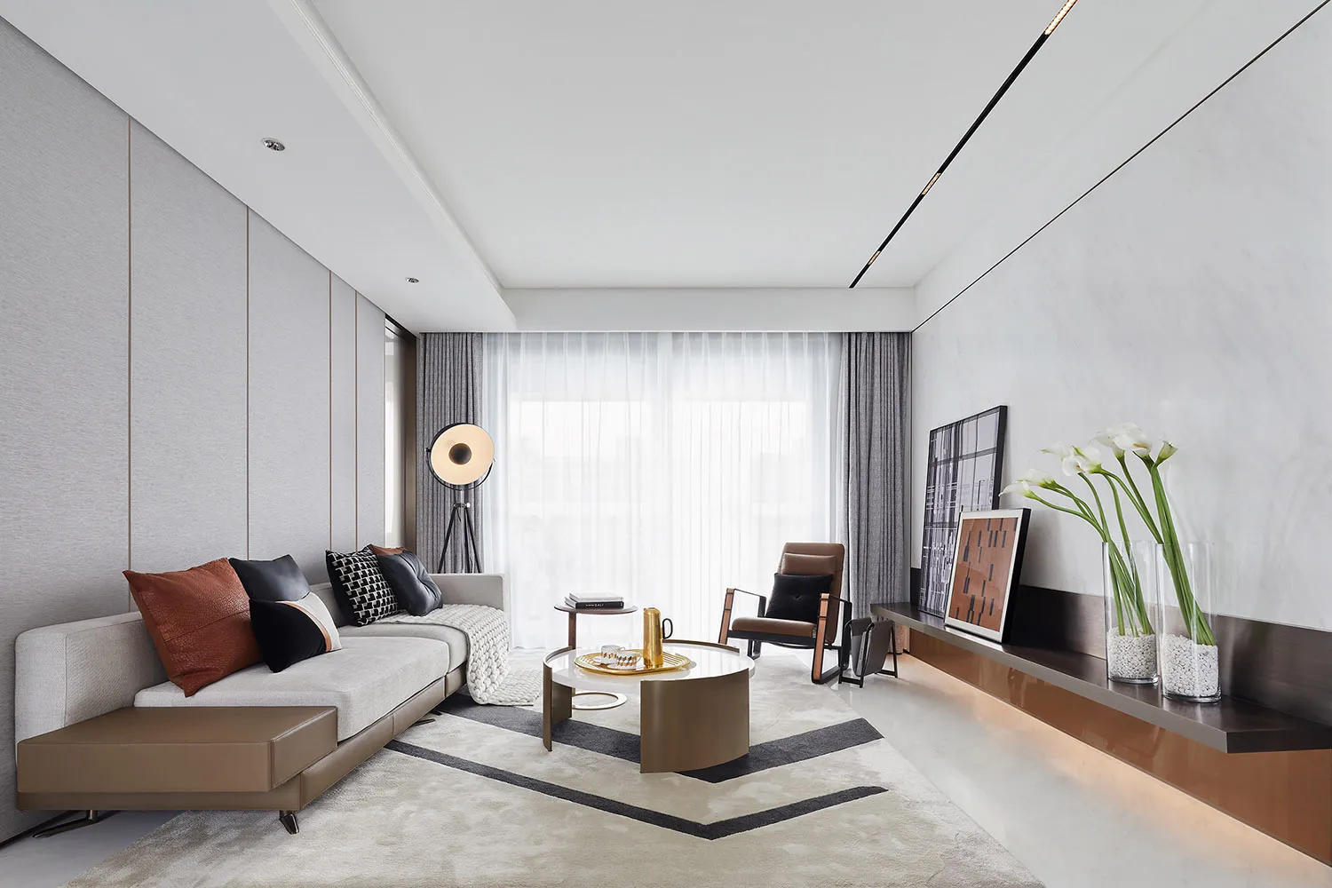 A modern living room featuring fabric seating, glass coffee table, and metal accents.