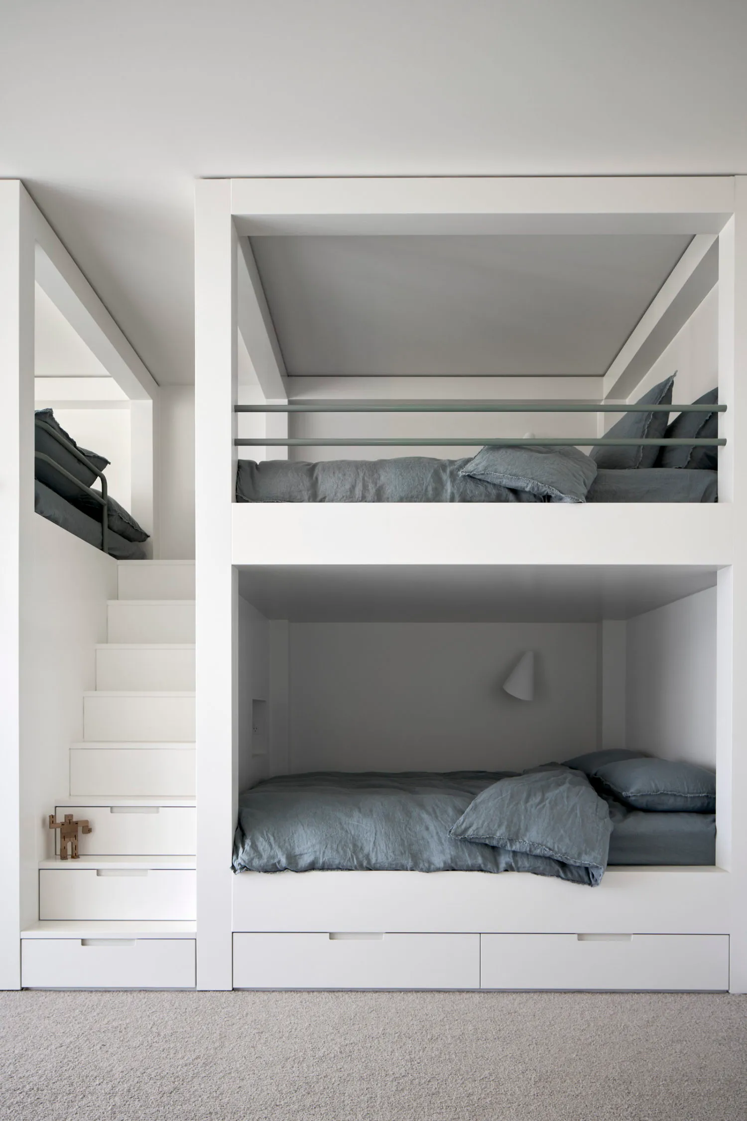 A modern minimalist bedroom with white walls and wooden bunk beds
