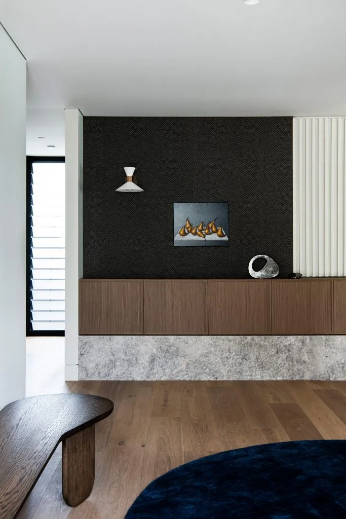 Modern living room with wooden floor, textured concrete walls, and contemporary furniture.