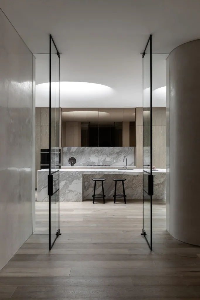 Modern kitchen with marble countertops and wooden flooring.