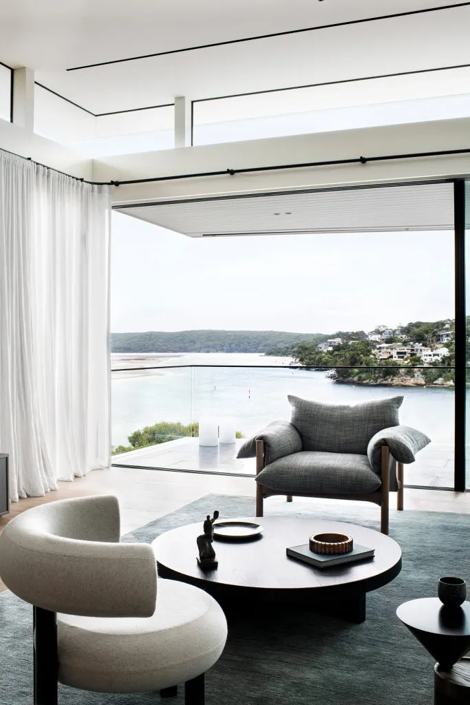 A modern living room featuring wooden cushions and a large window overlooking a scenic view of a river and hills.