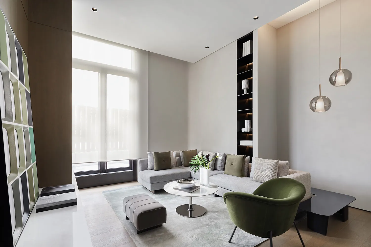 Modern minimalist living room with grey sectional sofa, round coffee table, green chair, and large windows.