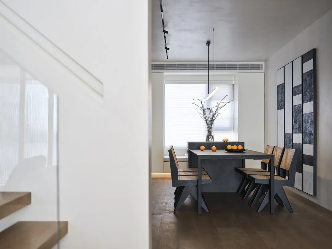 A modern industrial dining room with minimalist design, featuring a concrete dining table, wooden chairs, and a minimalist pe