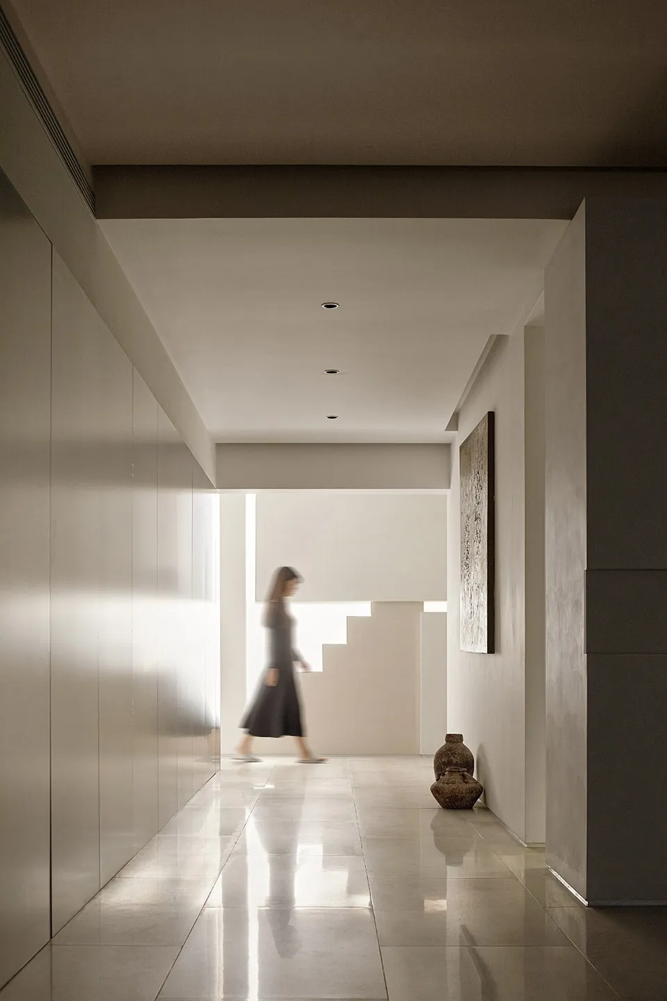 A minimalist hallway featuring a concrete staircase and flooring.