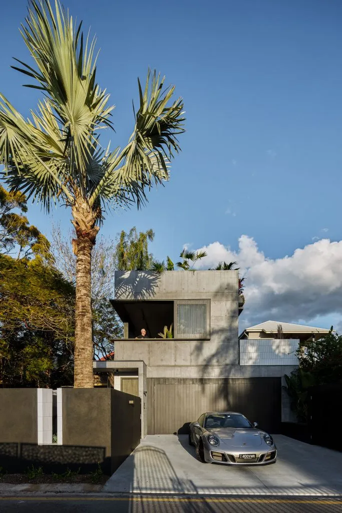 Modern residential house with a minimalist design, featuring concrete materials and greenery on the rooftop.