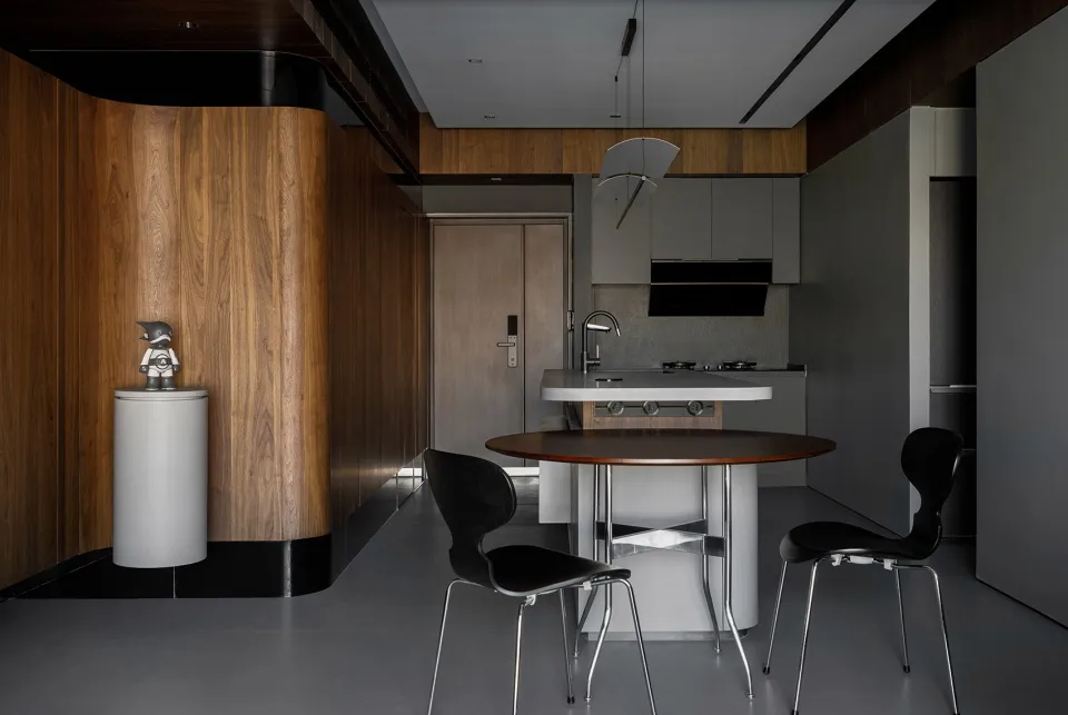 A modern kitchen with wood panel walls and a circular dining table.