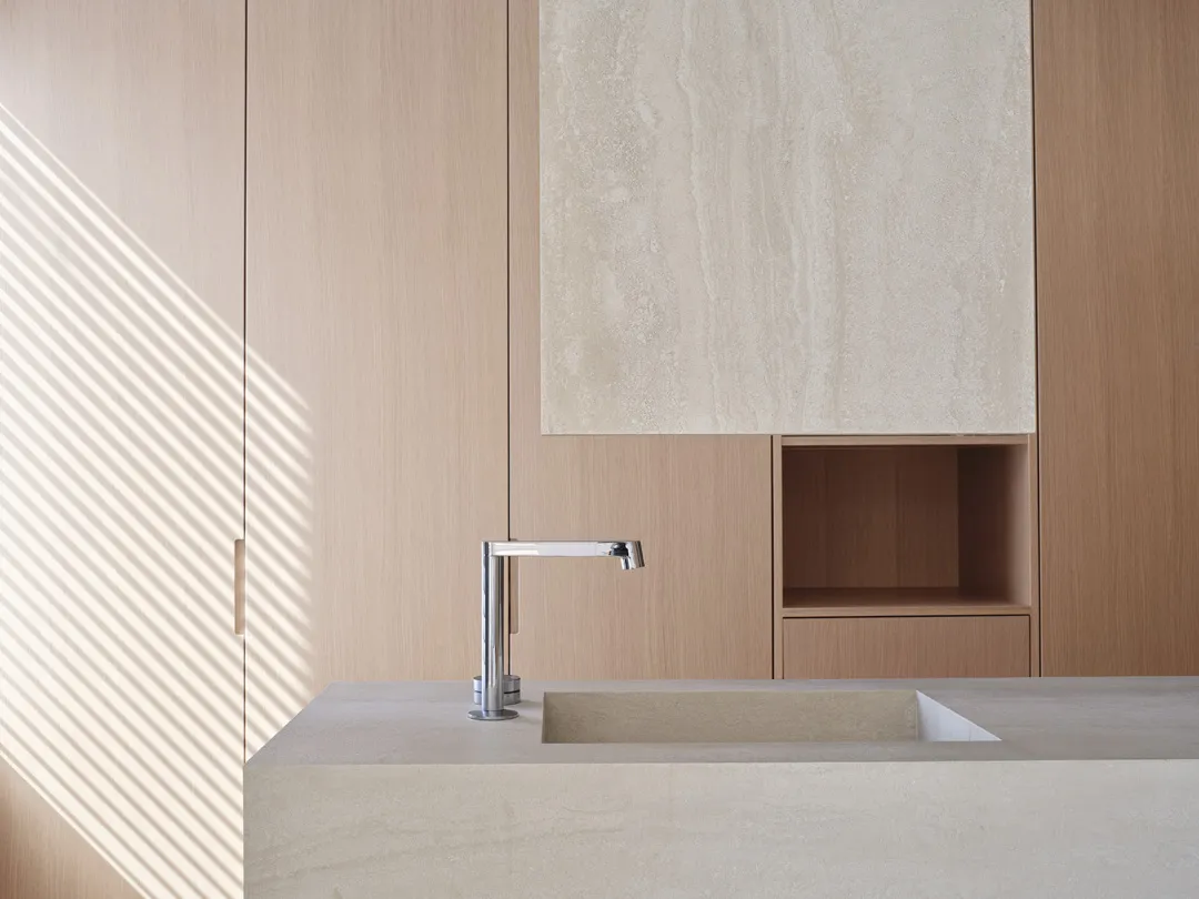 Modern minimalist kitchen featuring a concrete countertop and wooden cabinet with a sleek, minimalist faucet.