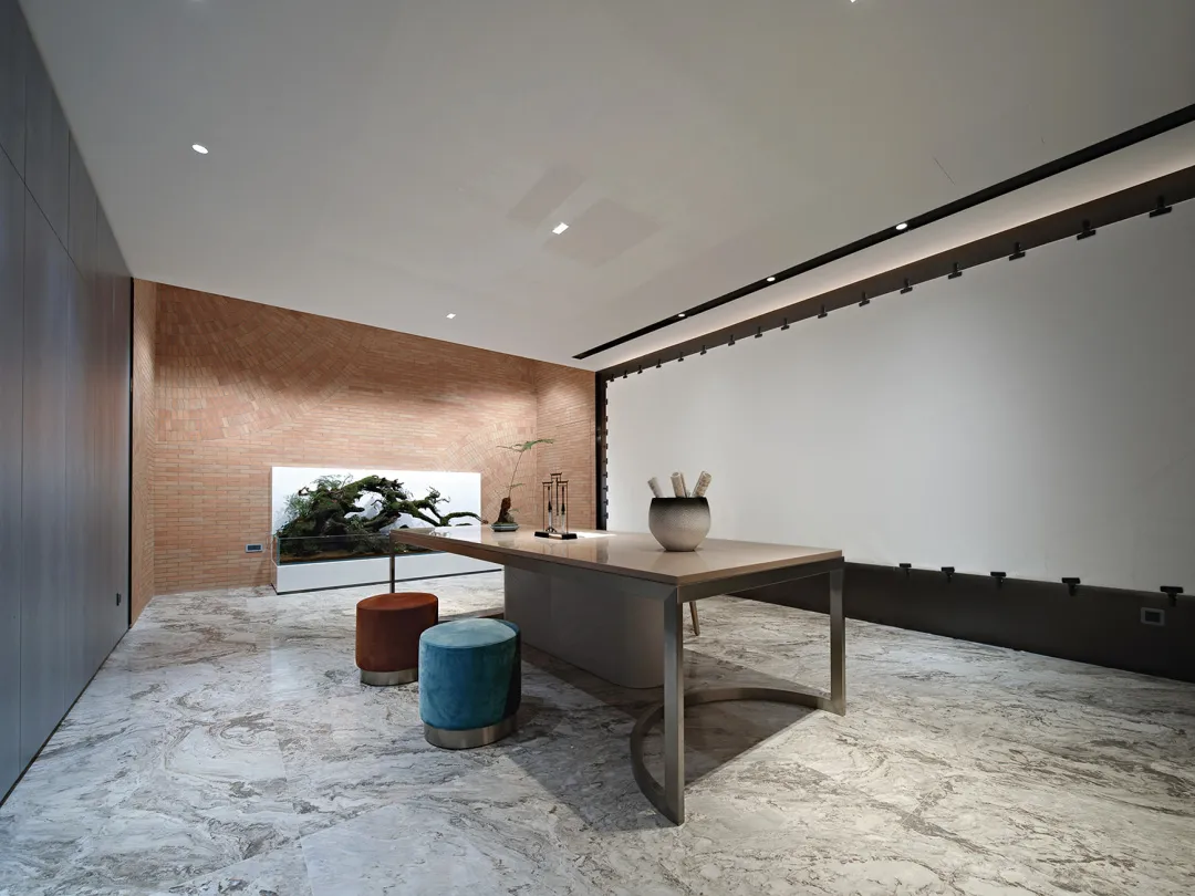 A modern office space featuring marble and cement finishes with minimalist furniture and a curved brick wall.