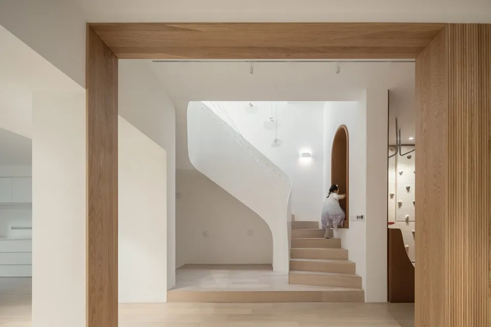 A minimalist interior design featuring wooden staircase and white walls with pendant lights.