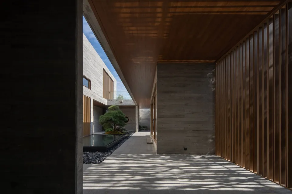 A minimalist design featuring a courtyard with concrete walls and wooden paneling.