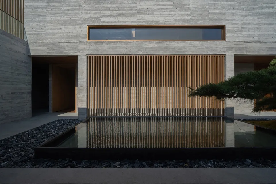 A modern outdoor space featuring concrete walls, wooden slats, and a water feature.