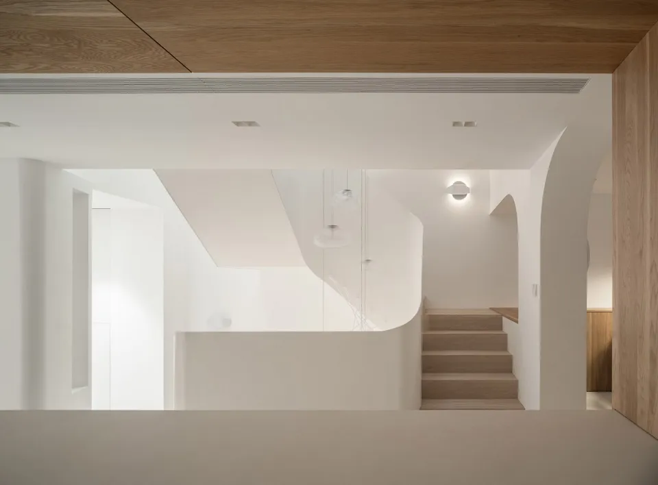 Modern interior design featuring a wooden staircase with a sleek, curved rail.