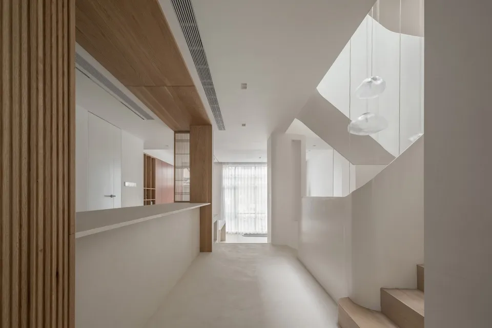 A modern living room with white walls, wooden elements, and a minimalist design.