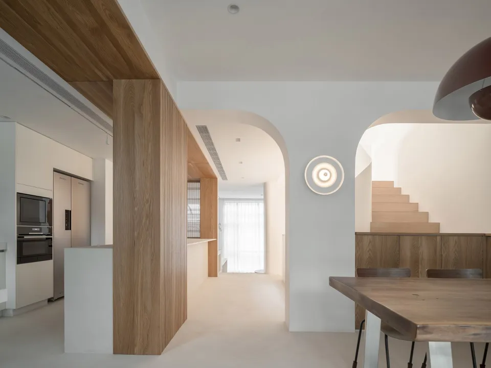 Modern minimalist dining room with wooden furniture and white walls.