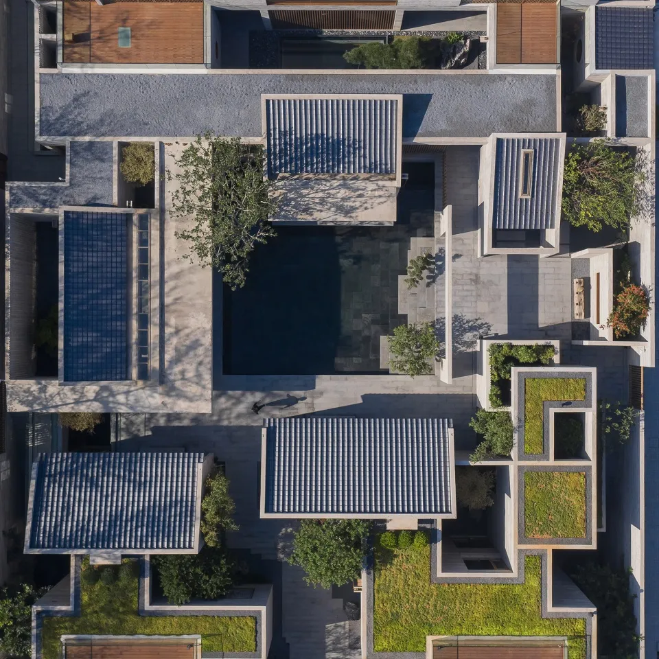 Aerial view of a modern residential courtyard with concrete structures, glass elements, and greenery.