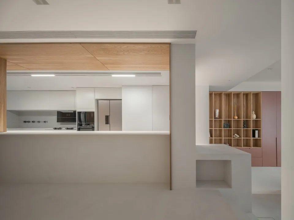 A modern kitchen with white walls and a white countertop, featuring a wooden ceiling and a wooden column.